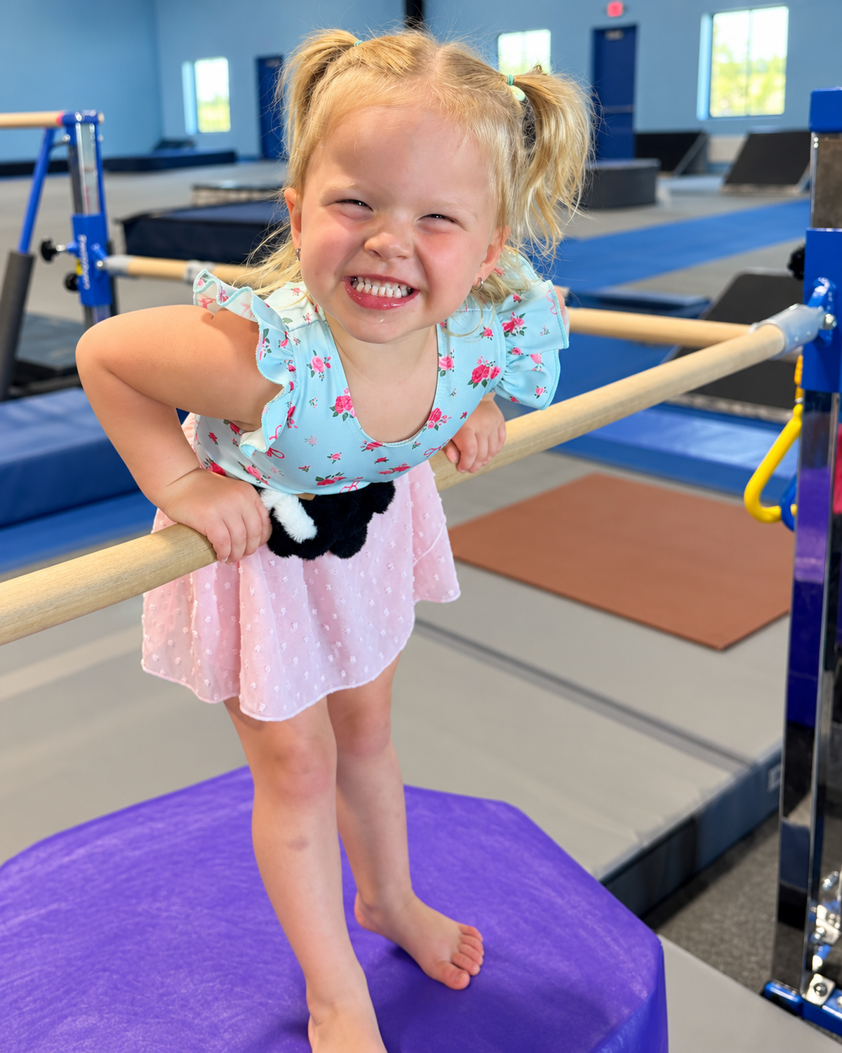 Smiling preschooler with pigtails leaning on a low practice bar